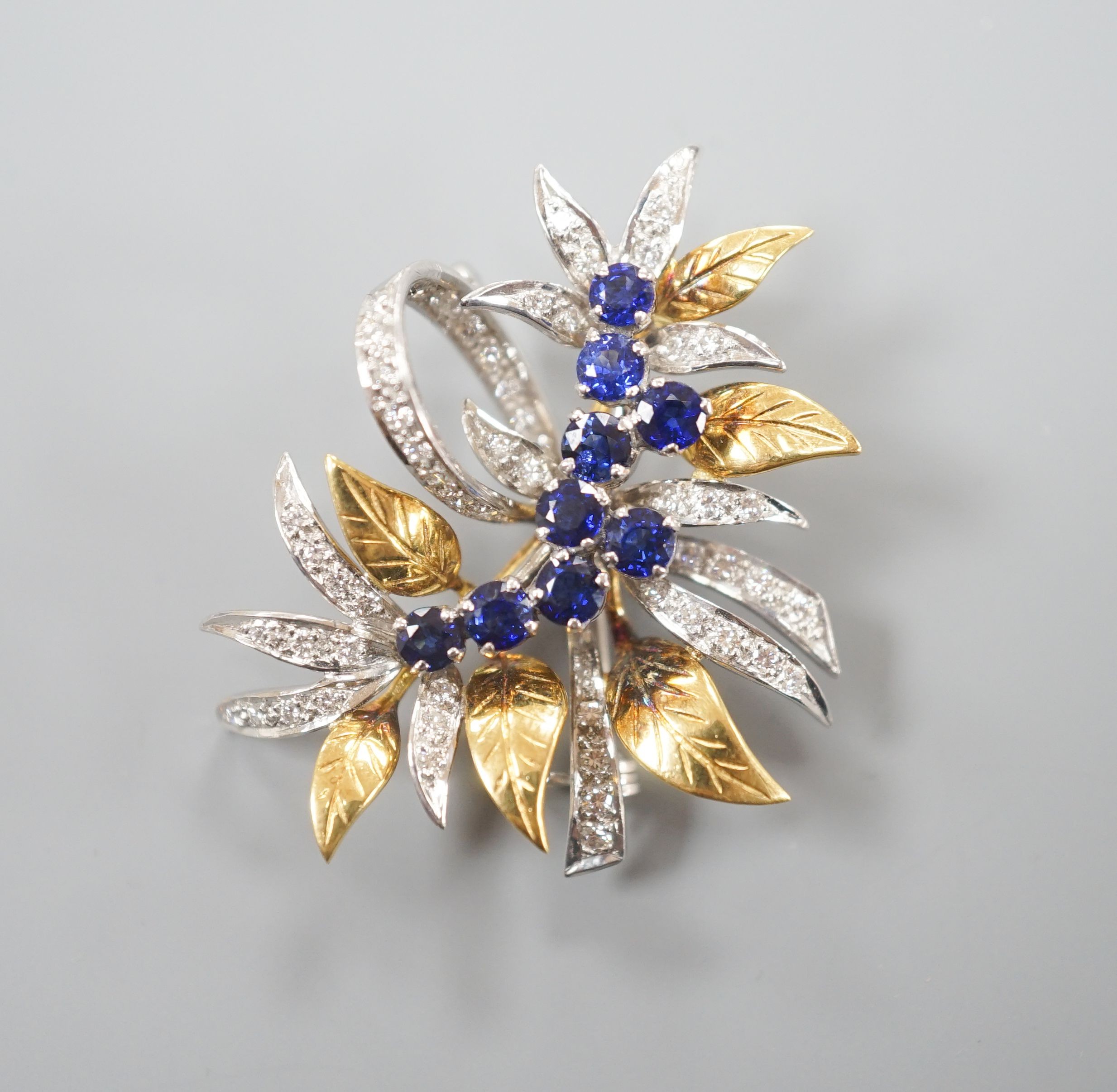 A modern 18ct two colour gold, sapphire and diamond set floral spray brooch, by Cropp & Farr, 38mm, gross weight 11.9 grams.